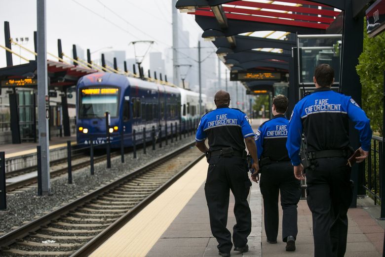 Fare enforcement officers walk the platform at the Sodo light rail station in 2014. (Bettina Hansen / The Seattle Times)
