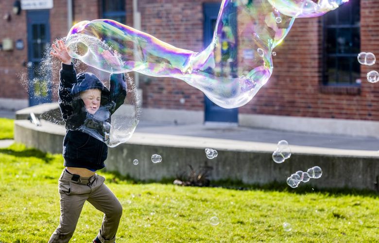 Dave Flanigan, 5, of Ballard, jumps with joy into a large bubble at Golden Gardens in Seattle during a sunny day on Saturday, Jan. 22, 2022. Forecasts suggest sunny yet cloudy days to come. LO
