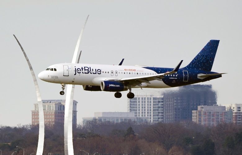 A JetBlue passenger flight passes the Air Force Memorial as it prepares to land at Reagan Washington National Airport in Arlington, Va., across the Potomac River from Washington, Wed., Jan. 19, 2022. The airline industry is raising the stakes in a showdown with AT&T and Verizon over plans to launch new 5G wireless service this week, warning that thousands of flights could be grounded or delayed if the rollout takes place near major airports. (AP Photo/J. Scott Applewhite) DCSA109 DCSA109