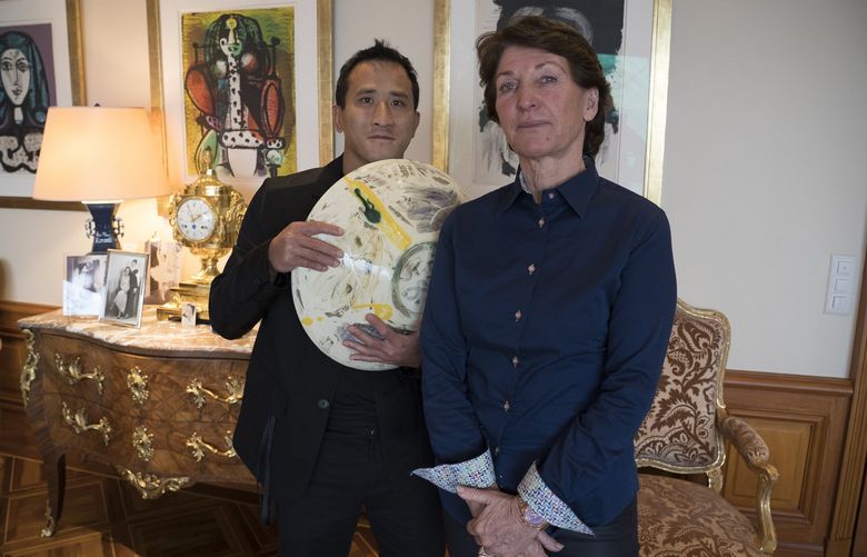Marina Picasso, right, granddaughter of artist Pablo Picasso, and her son Florian Picasso pose with a ceramic art-work of Pablo Picasso in Cologny near in Geneva, Switzerland, Tuesday, Jan. 25, 2022. Heirs of Pablo Picasso, the famed 20th-century Spanish artist, are vaulting into 21st-century commerce by selling 1,010 digital art pieces of one of his ceramic works that has never before seen publicly — riding a fad for “crypto†assets that have taken the art and financial worlds by storm. (AP Photo/Boris Heger) DMME102 DMME102