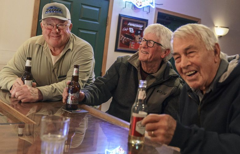 Reed Anfinson, right, who is often tagged as the liberal publisher of the The Swift County Monitor-News, meets up at a bar with John Zosel, from left, Mick Abner and Bill Harrison, part of a weekly gathering made up of mostly Republicans, in Benson, Minn., Tuesday, Nov. 30, 2021. It can be easy, looking around Benson, to think it is a land that time forgot. Bartenders often greet customers by name. The townâ€™s cafes feel like high school lunchrooms, with people wandering between tables to say hello. (AP Photo/David Goldman) MNDG258 MNDG258