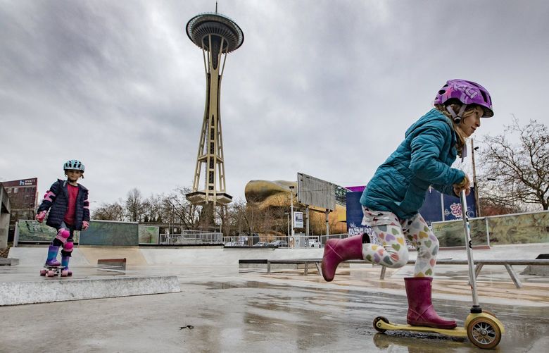 After their parents recently discovered the Seattle Center Skate Plaza, eight-year-old twins Gabi Nagel, right, and her brother Jonah, from Seattle, get some scootering and skateboarding in just before more rains come down, Sunday, Jan. 30, 2022 near the Space Needle. 219471