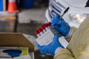 A medical worker marks a box of vials containing coronavirus test specimens at UW Medicine’s Sodo testing site in Seattle on Dec. 28. (Daniel Kim / The Seattle Times)