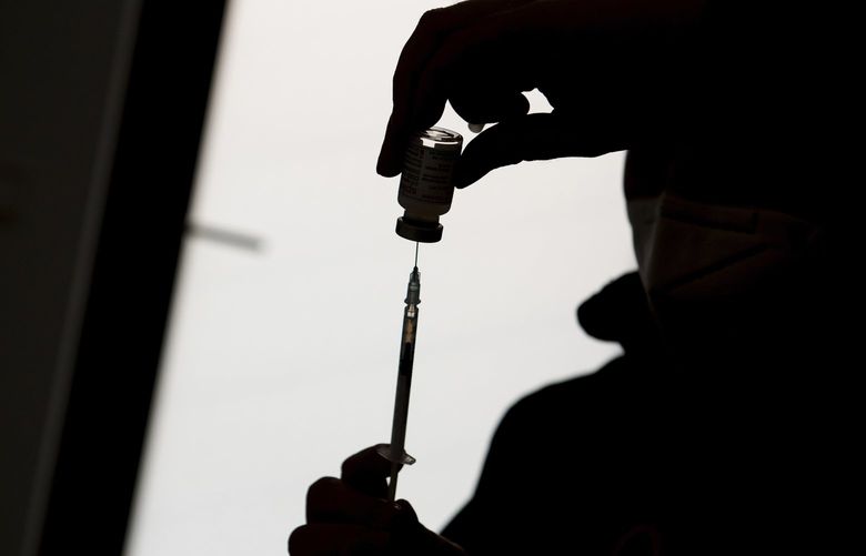 A syringe is drawn up with Moderna’s vaccine during a vaccination campaign at Cruise Center Steinwerder in Hamburg, Germany, Saturday, Jan. 8, 2022. (Daniel Bockwoldt/dpa via AP)
