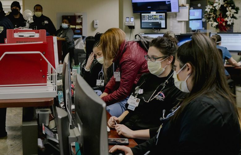 FILE – Nurses at a station before a shift change in the emergency department at Covenant Healthcare in Saginaw, Mich. on Dec. 16, 2021. Increased hospitalizations have put further stress on hospitals already struggling with staffing shortages. (Isadora Kosofsky/The New York Times) XNYT126 XNYT126
