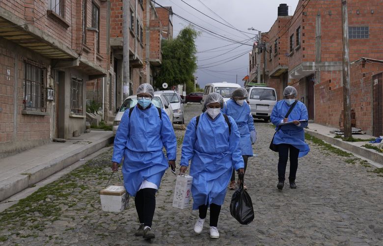 Healthcare workers walk during a door-to-door COVID-19 vaccination campaign, in La Paz, Bolivia, Sunday, Jan. 16, 2022. (AP Photo/Juan Karita) XJK105 XJK105