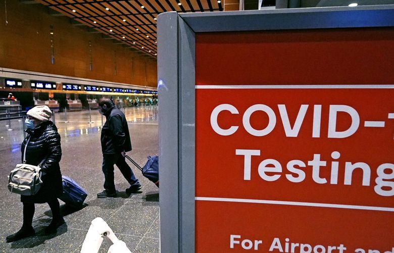 FILE – Travelers pass a sign near a COVID-19 testing site in Terminal E at Logan Airport, on Dec. 21, 2021, in Boston. A new AP-NORC poll shows that few Americans â€“ just 15% â€“ say they’ll consider the pandemic over only when COVID-19 is largely eliminated. By contrast, 83% say they’ll feel like the pandemic is over when it’s largely a mild illness, like the seasonal flu. (AP Photo/Charles Krupa, File) WX206 WX206