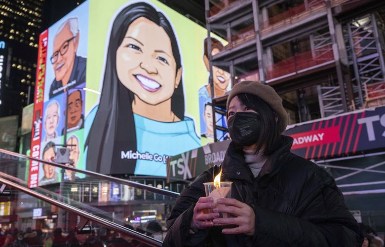 FILE – A person holds a candle during a vigil, Jan. 18, 2022, in New York’s Times Square, in honor of Michelle Alyssa Go, a victim of a subway attack several days earlier. Three random killings: a woman pushed in front of a train, another punched at a bus stop and a third stabbed to death while working alone in a store, and three homeless men charged with the crimes have reignited anger and frustration with the intractable issue of homelessness in New York and Los Angeles. (AP Photo/Yuki Iwamura, File) FX501 FX501