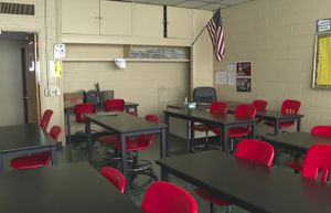 FILE – In this image made from video, an empty classroom is shown at David Ellis Academy in Detroit, Monday, Feb. 8, 2021. Facing a surge in COVID-19 cases, the Detroit Public Schools Community District joins a growing number of U.S. districts moving classes online. In Detroit, a district of 50,000 students, the move once again leaves parents juggling home and work schedules around the educational needs of their children. (AP Photo/Mike Householder File) RPMH201 RPMH201
