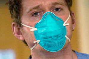 Registered nurse Scott McGieson wears an N95 mask as he walks out of a patient’s room in the acute care unit of Harborview Medical Center, Friday, Jan. 14, 2022, in Seattle. Washington Gov. Jay Inslee is deploying 100 members of the state National Guard to hospitals across the state amid staff shortages due to an omicron-fueled spike in COVID-19 hospitalizations. Inslee announced Thursday that teams will be deployed to assist four overcrowded emergency departments at hospitals in Everett, Yakima, Wenatchee and Spokane, and that testing teams will be based at hospitals in Olympia, Richland, Seattle and Tacoma. (AP Photo/Elaine Thompson)