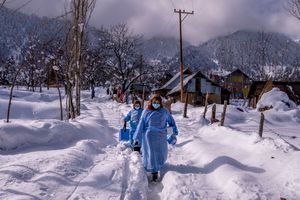 Fozia, foreground and Tasleema, Kashmiri healthcare workers, carry vaccines as they walk on a snow covered road after administering dose to an elderly woman during a COVID-19 vaccination drive in Budgam, southwest of Srinagar, Indian controlled Kashmir, Jan. 11, 2022. (AP Photo/Dar Yasin)
