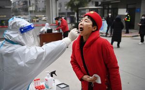 In this photo released by China’s Xinhua News Agency, a worker wearing protective gear gives a COVID-19 test to a woman at a testing site in Xi’an in northwestern China’s Shaanxi Province, Tuesday, Jan. 4, 2022. China is reporting a major drop in local COVID-19 infections in the northern city of Xi’an, which has been under a tight lockdown for the past two weeks. (Tao Ming/Xinhua via AP)