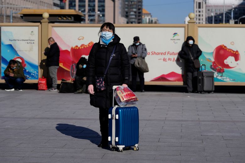 2022 年 1 月 28 日，星期五，中国北京，一位旅客提着行李箱在北京火车站外等候。北京冬奥会恰逢中国农历新年，新冠疫情再次爆发，促使中国当局呼吁公众留在他们所在的地方，而不是去家乡度过一年中最重要的家庭假期。 （美联社照片/吴汉冠）