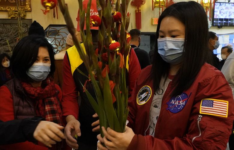 Worshippers buy flowers during the Lunar New Year celebrations at the Thien Hau Temple in the Chinatown neighborhood  of Los Angeles late Monday, Jan. 31, 2022. The celebration marks the Year of the Tiger in the Chinese Zodiac calendar. (AP Photo/Damian Dovarganes) CADD104 CADD104