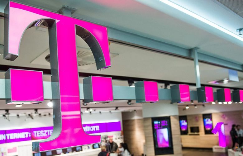 Customers browse mobile phone handsets as a sign sits above the entrance to a T-Mobile store, operated by Magyar Telekom Nyrt., in Budapest, Hungary, in 2015. 589940305