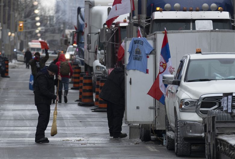 2022 年 2 月 2 日，星期三，一名抗议者在渥太华举行的卡车司机抗议活动中清扫了他的车辆周围的街道。 数以千计抗议疫苗授权和其他 COVID-19 限制措施的抗议者涌入首都，故意阻塞国会山周围的交通。 （阿德里安·威尔德/加拿大媒体通过美联社）