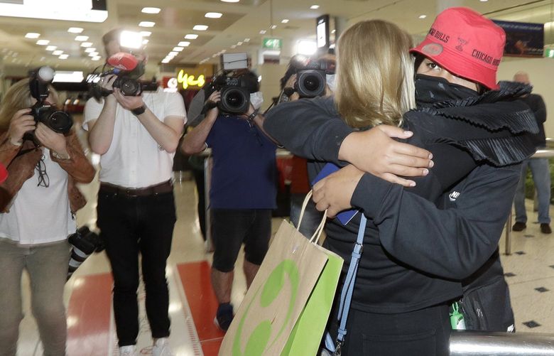 A woman arriving from New Zealand, right, is hugged by her stepmother at Sydney Airport in Sydney, Australia, Monday, April 19, 2021, as the much-anticipated travel bubble between Australia and New Zealand opens. (AP Photo/Rick Rycroft) XRR109
