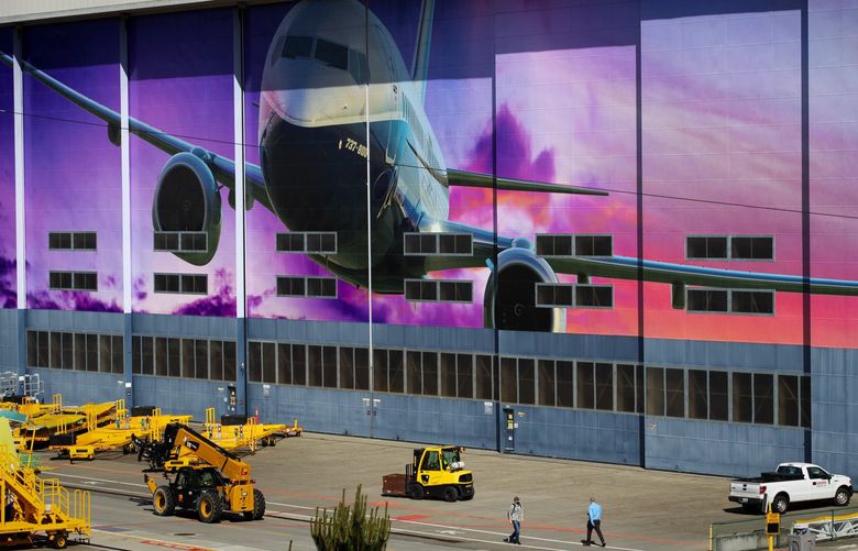 Workers walk in front of a factory door at Boeing’s Renton plant Wednesday morning, May 27, 2020. Boeing announced to employees Wednesday a first batch of almost 7,000 involuntary layoffs in the U. S., which added to more than 5,500 voluntary layoffs. It will cut almost 12,300 jobs company-wide. 214067