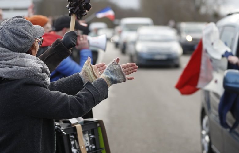 People applaud a convoy departing for Paris, Friday, Feb.11, 2022 in Strasbourg, eastern France. Authorities in France and Belgium have banned road blockades threatened by groups organizing online against COVID-19 restrictions. The events are in part inspired by protesters in Canada. Citing “risks of trouble to public order,” the Paris police department banned protests aimed at “blocking the capital” from Friday through Monday. (AP Photo/Jean-Francois Badias) STR102 STR102