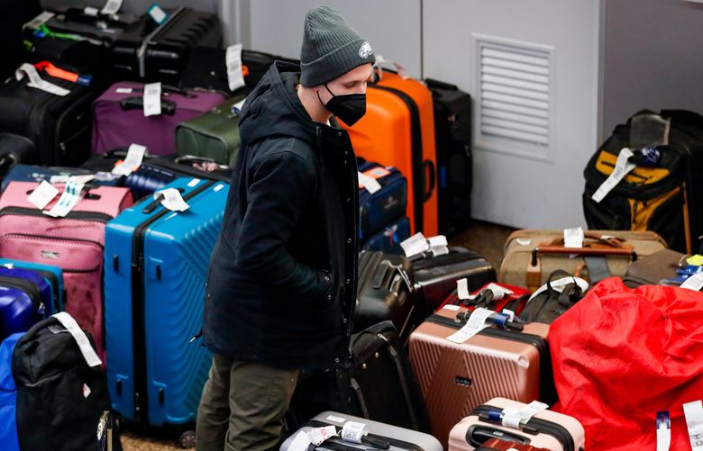 Konrad Thallner looks for his bags in the Alaska Airlines baggage-claim area on Dec. 31, 2021 at Seattle-Tacoma International Airport. Thallner flew into Seattle from New Jersey on Dec. 26 and was still waiting for his bags days later. (Jennifer Buchanan / The Seattle Times)