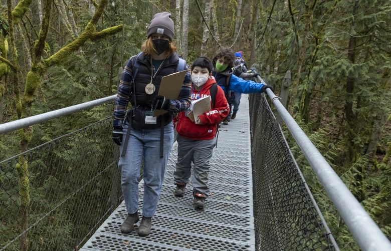 Marina Hydeman, (l) a UW grad student and instructor at IslandWood on Bainbridge Island, leads students over the 190â€™ long suspension bridge at IslandWood during a hike Wednesday, February 2, 2022. The hike is just one of the activities at the School Overnight Program they are attending.  

The kids arrived Tuesday and will stay through until Thursday. That is the traditional program length of the School Overnight Program.

They are a mix of 4th, 5th, and 6th graders and are  from Lake Quinault.

Over the three day period, the students do a whole variety of things â€“ check out the garden where they will taste plants growing there and bake bread,  hang out at the pond and learn about macroinvertebrates, and hike on the trails and on the campâ€™s suspension bridge as well as climb the 120â€™ canopy tower.

Each instructor sets their plan for the day based on their own group and the previous dayâ€™s work

A new house bill could expand outdoor education statewide. 219479
