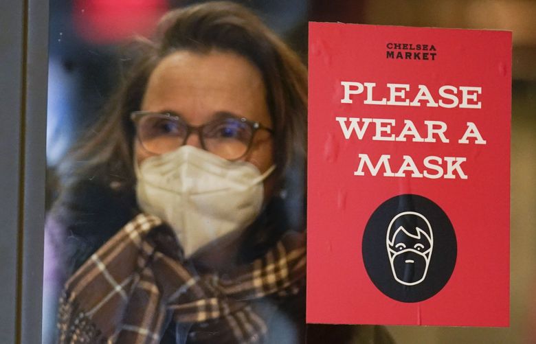 A sign asks shoppers to wear masks in New York, Wednesday, Feb. 9, 2022. New York Gov. Kathy Hochul announced Wednesday that the state will end a COVID-19 mask mandate requiring face coverings in most indoor public settings, but will keep masking rules in place in schools for now. (AP Photo/Seth Wenig) NYSW107 NYSW107