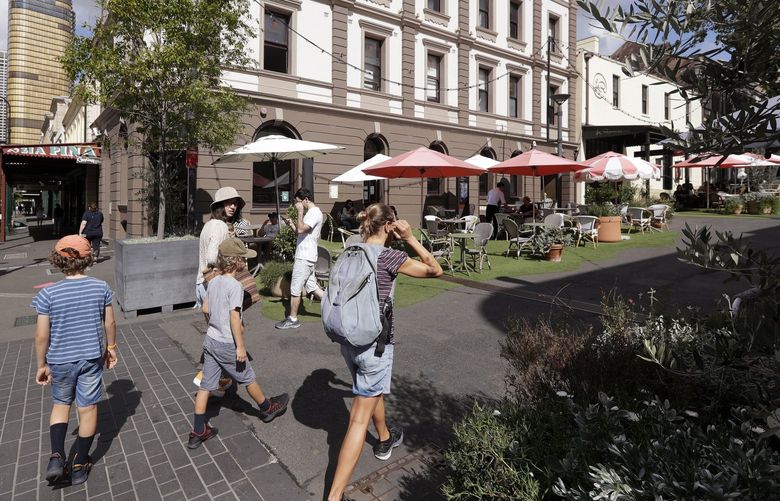 People walk around a popular eating area in Sydney, Australia, Tuesday, April 6, 2021. New Zealand announced the start date for a long-anticipated travel bubble between Australia and New Zealand that will allow people to travel between the two countries without going through quarantine, allowing families to reunite and giving a big boost to the struggling tourism industry will begin April 19. (AP Photo/Rick Rycroft)
