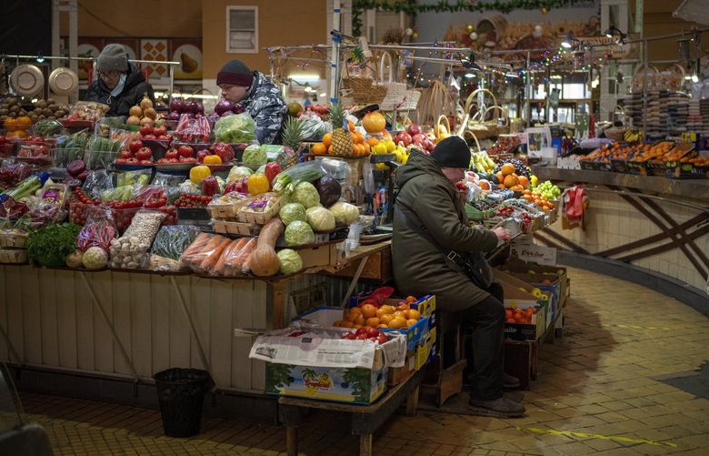 FILE – Vendors wait for customers at their fruit market stall in downtown Kyiv, Ukraine, Monday, Feb. 14, 2022. With Russian troops encircling much of the country, Ukrainian businesses large and small no longer plan for the future â€” they can barely foresee what will happen week to week. (AP Photo/Emilio Morenatti, File) XAZ911 XAZ911