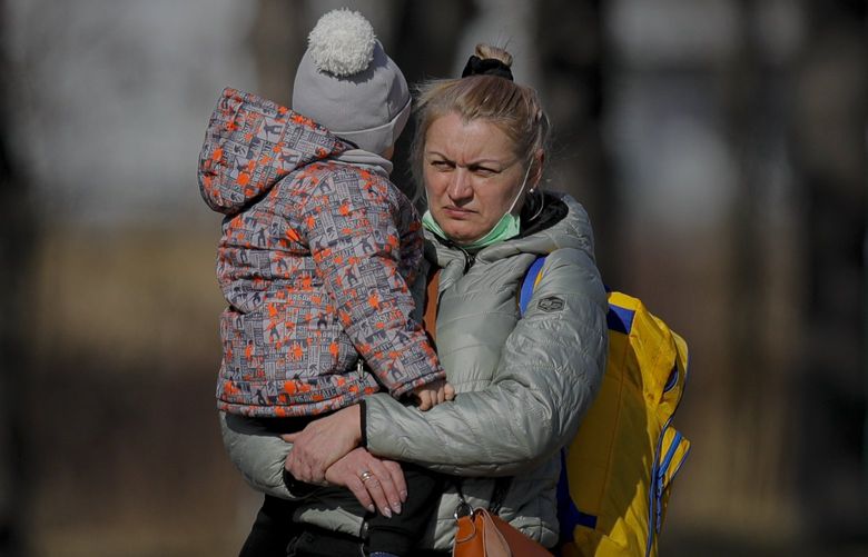 A Ukrainian woman holds a child after crossing the border from Ukraine at the Romanian-Ukrainian border, in Siret, Romania, Friday, Feb. 25, 2022. Thousands of Ukrainians are fleeing from war by crossing their borders to the west in search of safety. They left their country as Russia pounded their capital and other cities with airstrikes for a second day on Friday. Cars were backed up for several kilometers (miles) at some border crossings as authorities in Poland, Slovakia, Hungary, Romania and Moldova mobilized to receive them, offering them shelter, food and legal help. (AP Photo/Andreea Alexandru) XAA802 XAA802