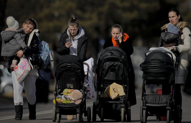 Women push baby strollers after crossing the border from Ukraine at the Romanian-Ukrainian border, in Siret, Romania, Friday, Feb. 25, 2022. Thousands of Ukrainians are fleeing from war by crossing their borders to the west in search of safety. They left their country as Russia pounded their capital and other cities with airstrikes for a second day on Friday. Cars were backed up for several kilometers (miles) at some border crossings as authorities in Poland, Slovakia, Hungary, Romania and Moldova mobilized to receive them, offering them shelter, food and legal help. (AP Photo/Andreea Alexandru) XAA815 XAA815