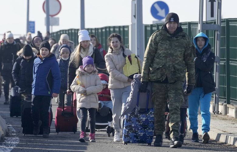 A Polish border guard assists refugees from Ukraine as they arrive to Poland at the Korczowa border crossing, Poland, Saturday, Feb. 26, 2022. (AP Photo/Czarek Sokolowski) XDB117 XDB117