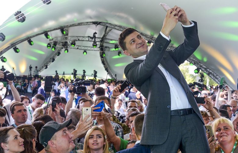 FILE – Ukrainian President Volodymyr Zelenskyy takes a selfie at the first congress of his party called Servant of the People in the city Botanical Garden, Kiev, Ukraine, June 9, 2019. (AP Photo/Zoya Shu, File) NYAG807 NYAG807