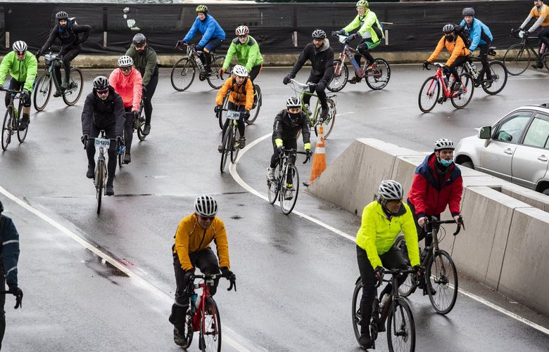 Cyclists returning to Seattle’s Colman Dock offer a splash of color on a grey Sunday afternoon after disembarking the MV Tacoma ferry from Bainbridge Island, where Cascade Bicycle Club hosts the 50th Chilly Hilly 33-mile ride, Sunday, Feb. 27, 2022.  219713