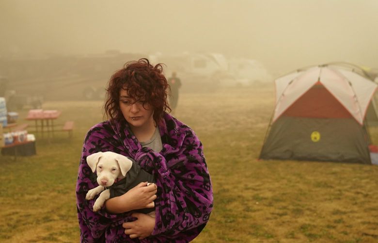 FILE – Shayanne Summers holds her dog, Toph, while wrapped in a blanket after several days of staying in a tent at an evacuation center at the Milwaukie-Portland Elks Lodge, Sunday, Sept. 13, 2020, in Oak Grove, Ore. The United Nations on Monday, Feb. 28, 2022, released a new report on climate change. (AP Photo/John Locher, File) NYAG605 NYAG605