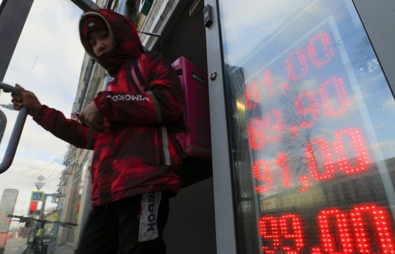 FILE – A food delivery man leaves an exchange office with screen showing the currency exchange rates of U.S. Dollar and Euro to Russian Rubles in Moscow, Russia, Thursday, Feb. 24, 2022. The ruble plunged to a record low of less than 1 U.S. cent in value Monday after Russia was cut off from the global bank payments system in retaliation for Moscowâ€™s invasion of Ukraine. (AP Photo/Alexander Zemlianichenko Jr.,File) BKWS301 BKWS301
