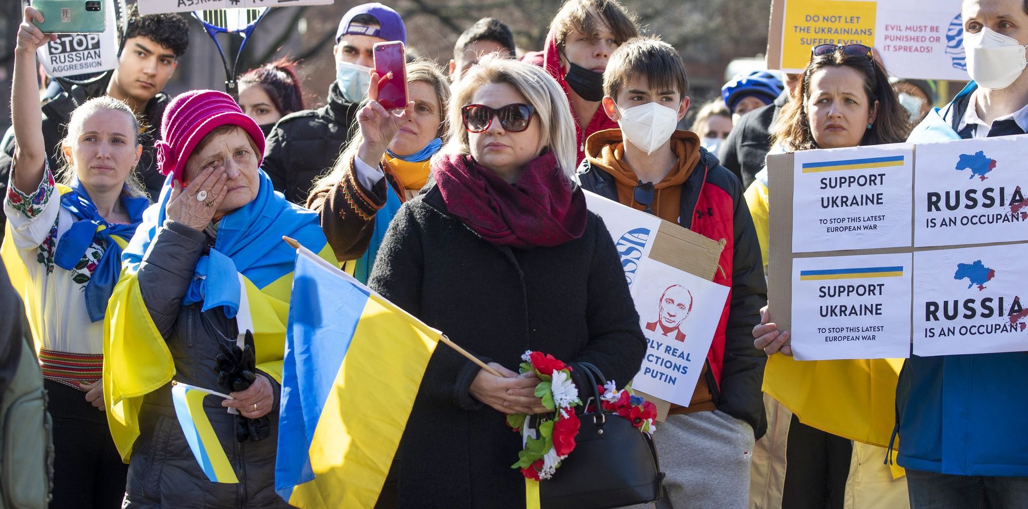 A group of people holding signs and flags rally against the war in Ukraine at the University of Washington.