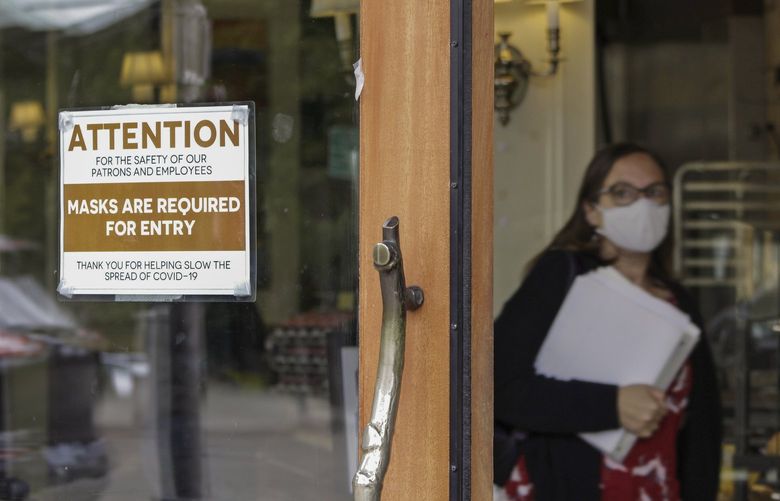 FILE – In this May 21, 2021 file photo, a sign reminds customers to wear their masks at a bakery in Lake Oswego, Ore. As of Wednesday, Aug. 18, 2021, just 41 intensive care unit beds were available in Oregon, as COVID-19 cases continue to climb and hospitals near capacity in a state that was once viewed as a pandemic success story. Oregon, which earlier had among the lowest cases per capita, is now shattering its COVID-19 hospitalization records day after day. (AP Photo/Gillian Flaccus, File)