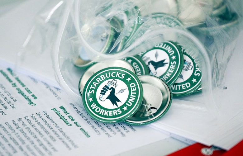 Pro-union pins sit on a table during a watch party for Starbucks’ employees union election, Dec. 9, 2021, in Buffalo, N.Y. Starbucks has fired seven employees who were leading an effort to unionize a Memphis, Tennessee, store. The Seattle coffee giant said Tuesday, Feb. 8, 2022 that the employees violated company policy by reopening a store after closing time and inviting non-employees to come inside and move throughout the store, including behind the counter and in back rooms. The employees used the store to do an interview with a local television station about their unionizing effort. (AP Photo/Joshua Bessex, File) NYPS209