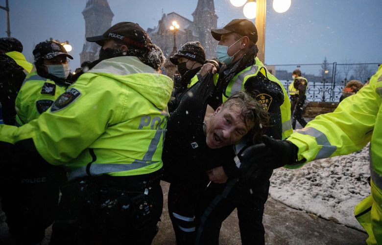 A man is arrested by police as protesters and supporters gather as a protest against COVID-19 measures that has grown into a broader anti-government protest continues to occupy downtown Ottawa, Ontario, on Thursday, Feb. 17, 2022. (Cole Burston/The Canadian Press via AP) CLB116 CLB116
