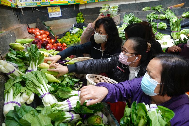 周三，戴着口罩的顾客在香港一家湿货市场商店购买新鲜蔬菜。 香港领导人周二宣布了该市迄今为止最严格的社交距离限制，包括对私人聚会的前所未有的限制，因为每天新增病例超过 600 例。（美联社照片/Vincent Yu）
