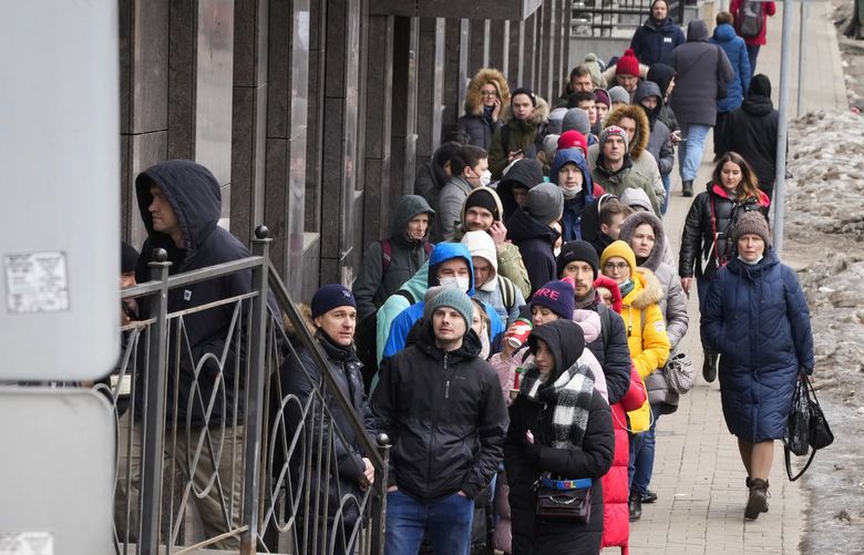 People stand in line to withdraw U.S. dollars and Euros from an ATM in St. Petersburg, Russia, Friday, Feb. 25, 2022. Ordinary Russians faced the prospect of higher prices and crimped foreign travel as Western sanctions over the invasion of Ukraine sent the ruble plummeting, leading uneasy people to line up at banks and ATMs on Monday in a country that has seen more than one currency disaster in the post-Soviet era. (AP Photo/Dmitri Lovetsky) XDL106 XDL106