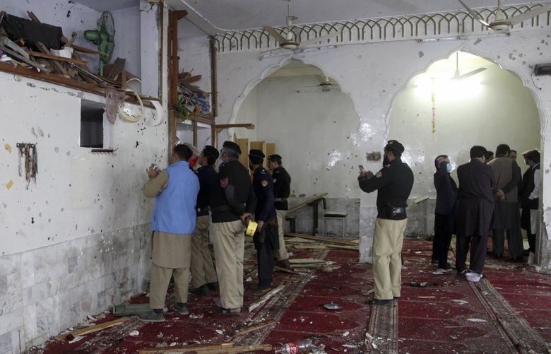 Police officers examine the site of bomb explosion inside a mosque in Peshawar, Pakistan, Friday, March 4, 2022. A powerful bomb exploded inside a Shiite Muslim mosque in Pakistan’s northwestern city of Peshawar on Friday, killing scores of worshippers and wounding dozens more, many of them critically, police said. (AP Photo/Muhammad Sajjad) ISL121 ISL121