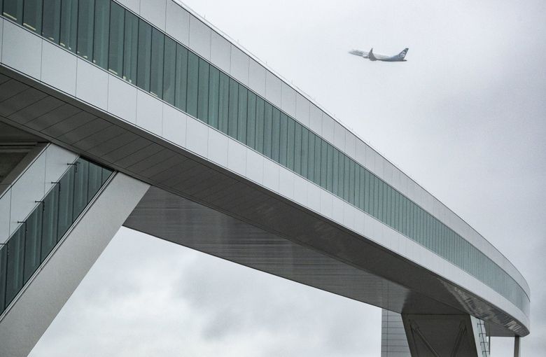 An Alaska Airlines flight takes off past the passenger walkway attached to the new International Arrivals Facility at Seattle-Tacoma International Airport. (Ken Lambert / The Seattle Times)