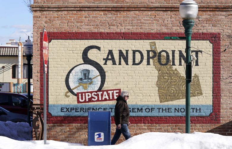 A pedestrian walks past a mural, Monday, Feb. 7, 2022, in downtown Sandpoint, Idaho. The Mayor of Sandpoint and many residents worry that the trend of a growing number of real estate companies advertising to conservatives that they can help people move out of liberal bastions like Seattle and San Francisco and find homes in places like rural Idaho is not good for their community. (AP Photo/Ted S. Warren) IDTW403 IDTW403