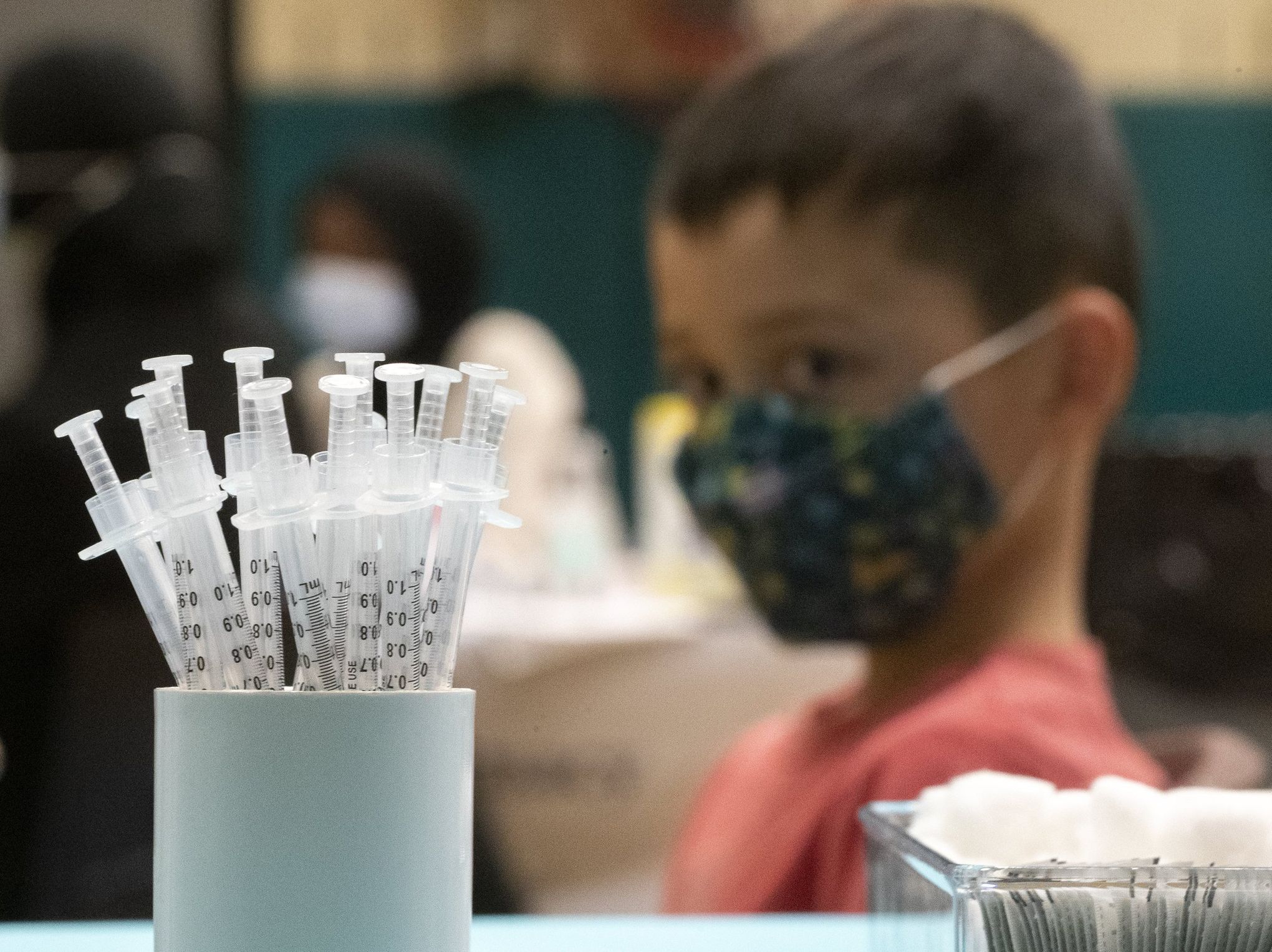 A student looks at a cup filled with COVID vaccines