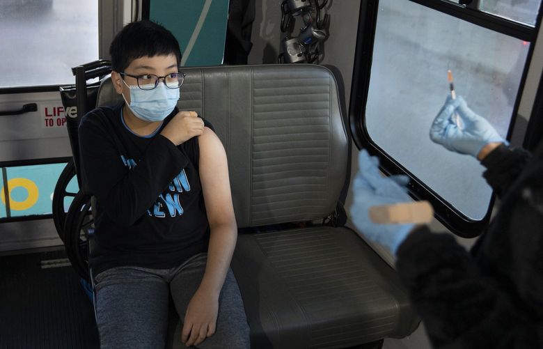 FILE – A child prepares for a Pfizer-BioNTech COVID-19 vaccination in a van outside a school in Queens, Nov. 12, 2021. Both Pfizer and Moderna plan to soon report results from trials of their vaccines in young children. (James Estrin/The New York Times) XNYT101 XNYT101