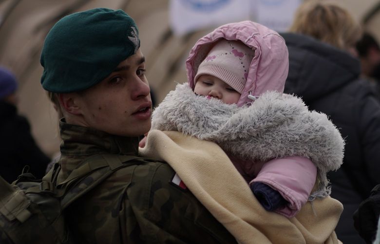 A Polish soldier holds a baby as refugees fleeing war in neighboring Ukraine arrive at the Medyka crossing border, Poland, Thursday, March 10, 2022. (AP Photo/Daniel Cole) XDC103 XDC103
