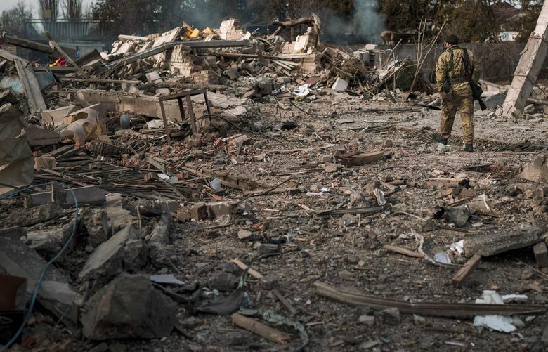 A volunteer of the Ukrainian Territorial Defense Forces walks on the debris of a car wash destroyed by a Russian bombing in Baryshivka, east of Kyiv, Ukraine, Friday, March 11, 2022. (AP Photo/Felipe Dana) NYAG515