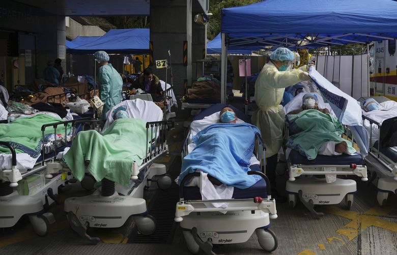 Patients lie on hospital beds as they wait at a temporary makeshift treatment area outside Caritas Medical Centre in Hong Kong, Friday, Feb. 18, 2022. (AP Photo/Kin Cheung) AGV130 AGV130