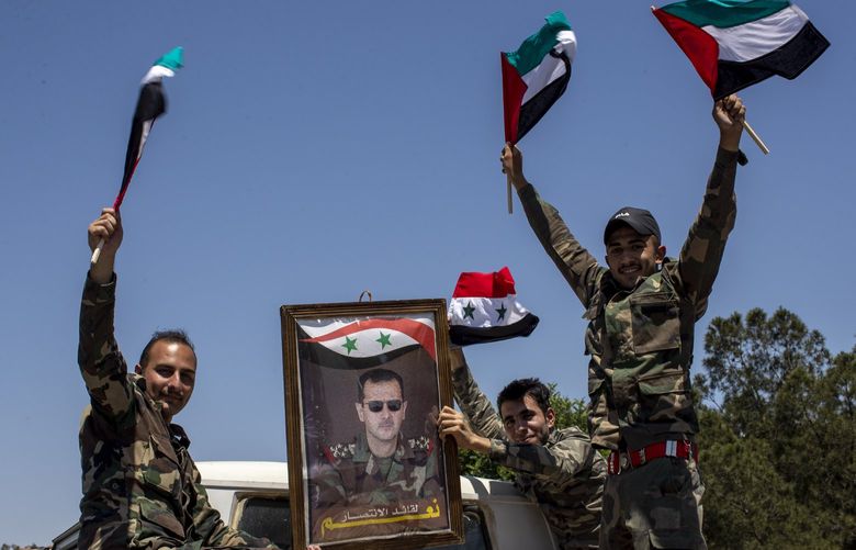 FILE – Syrian soldiers hold up Baath party flags and a portrait of Syrian President Bashar Assad with Arabic that reads “Yes to the leader of victory,” as they celebrate outside the town of Douma, in the eastern Ghouta region, near the Syrian capital Damascus, Syria, Wednesday, May 26, 2021. With its war on Ukraine now in its third week, Russian President Vladimir Putin on Friday, March 11, 2022, approved bringing in volunteer fighters from the Middle East into the conflict.   (AP Photo/Hassan Ammar, File) CAIDK602 CAIDK602